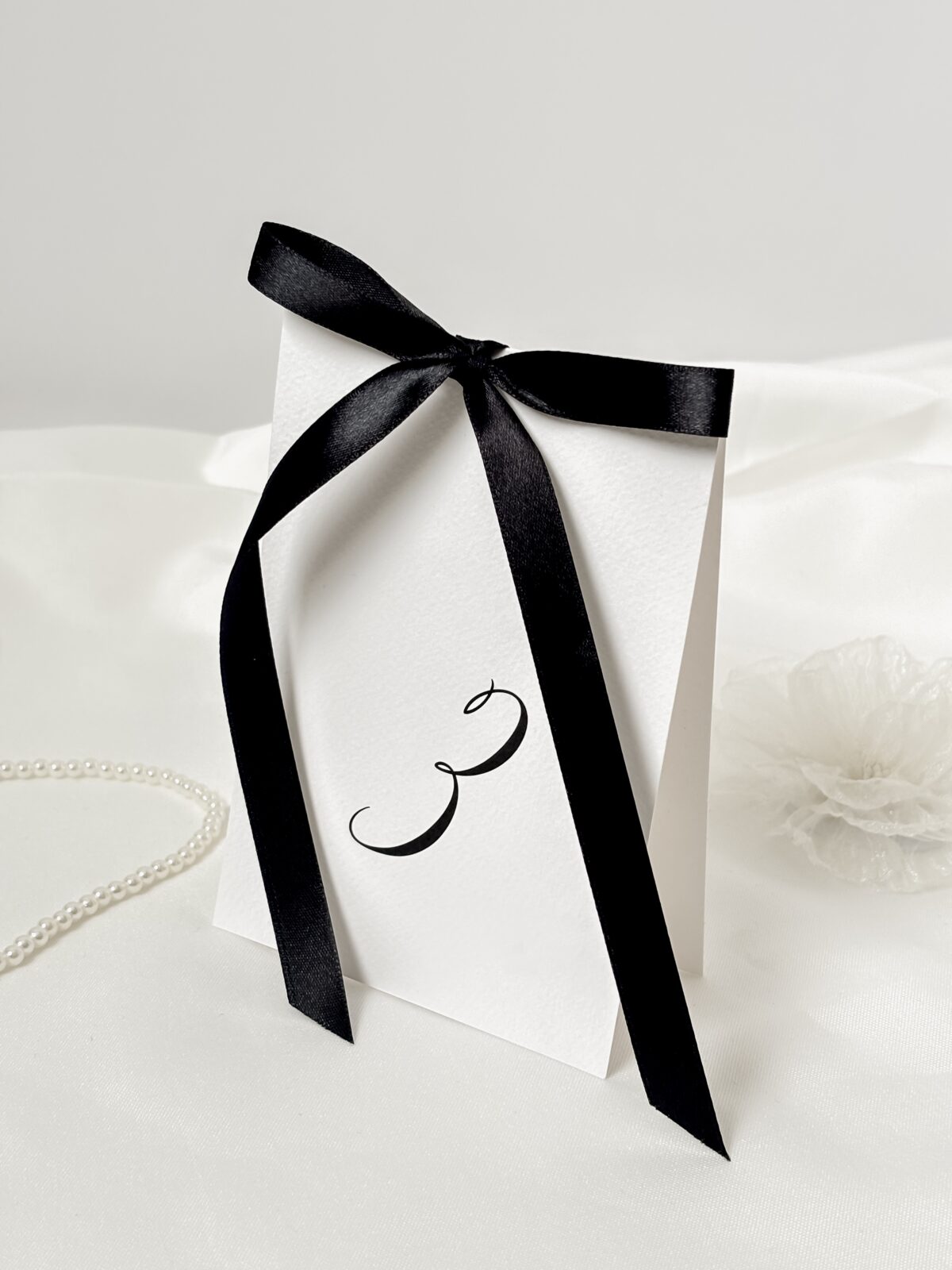 Karta z numerem stołu z czarną kokardą