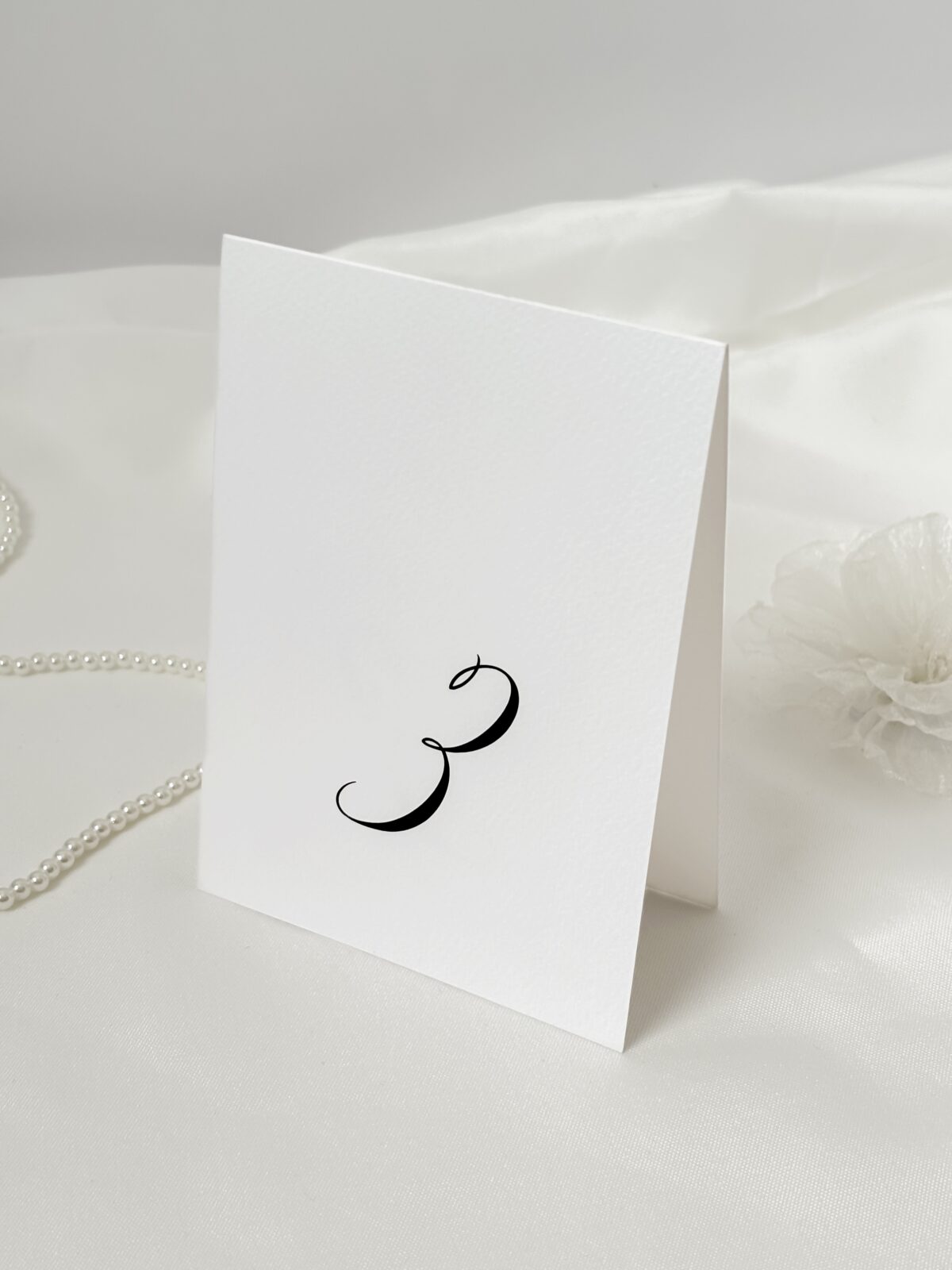 Numer stolika weselnego w eleganckiej czcionce na białym papierze