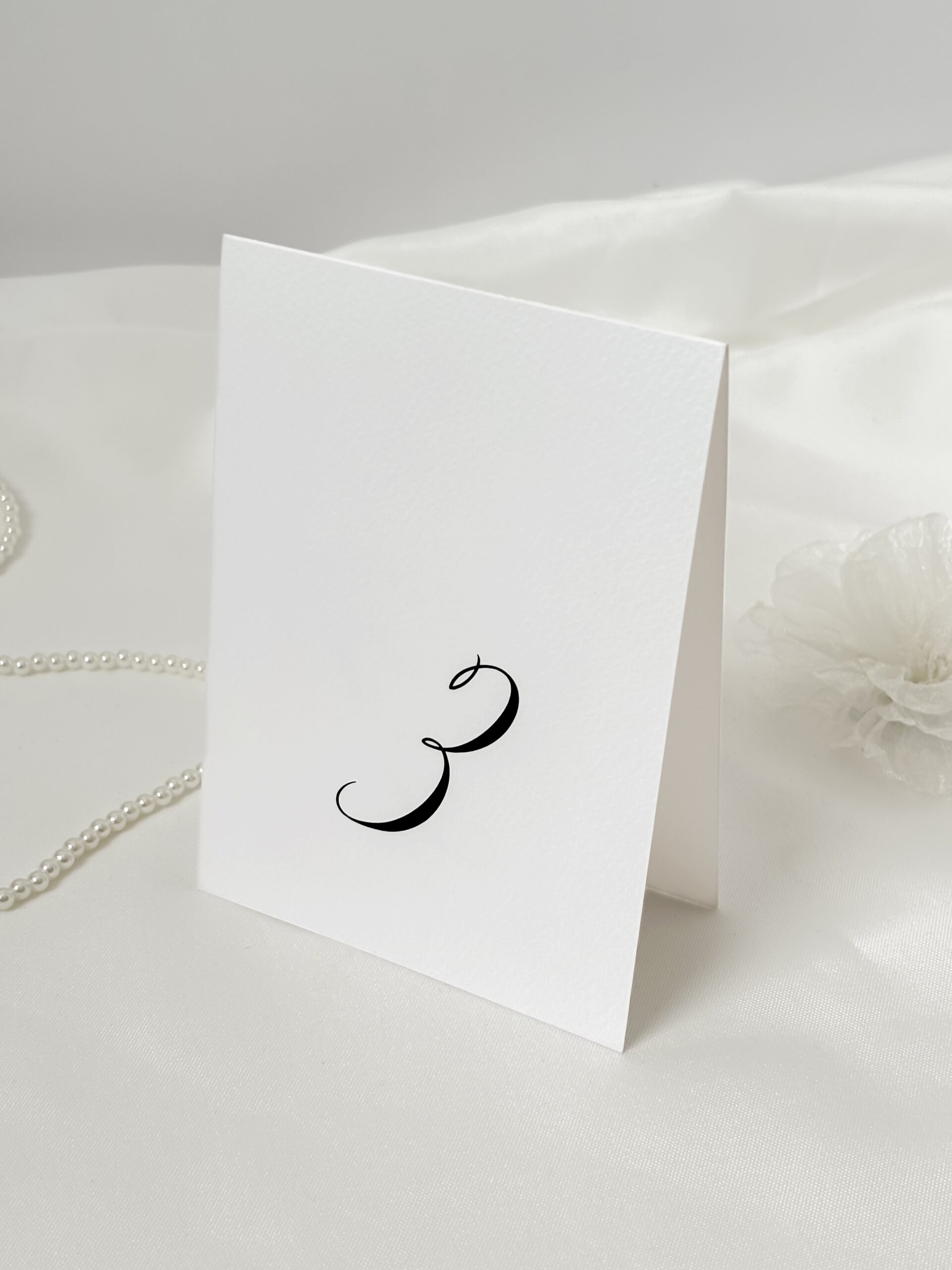 Numer stolika weselnego w eleganckiej czcionce na białym papierze