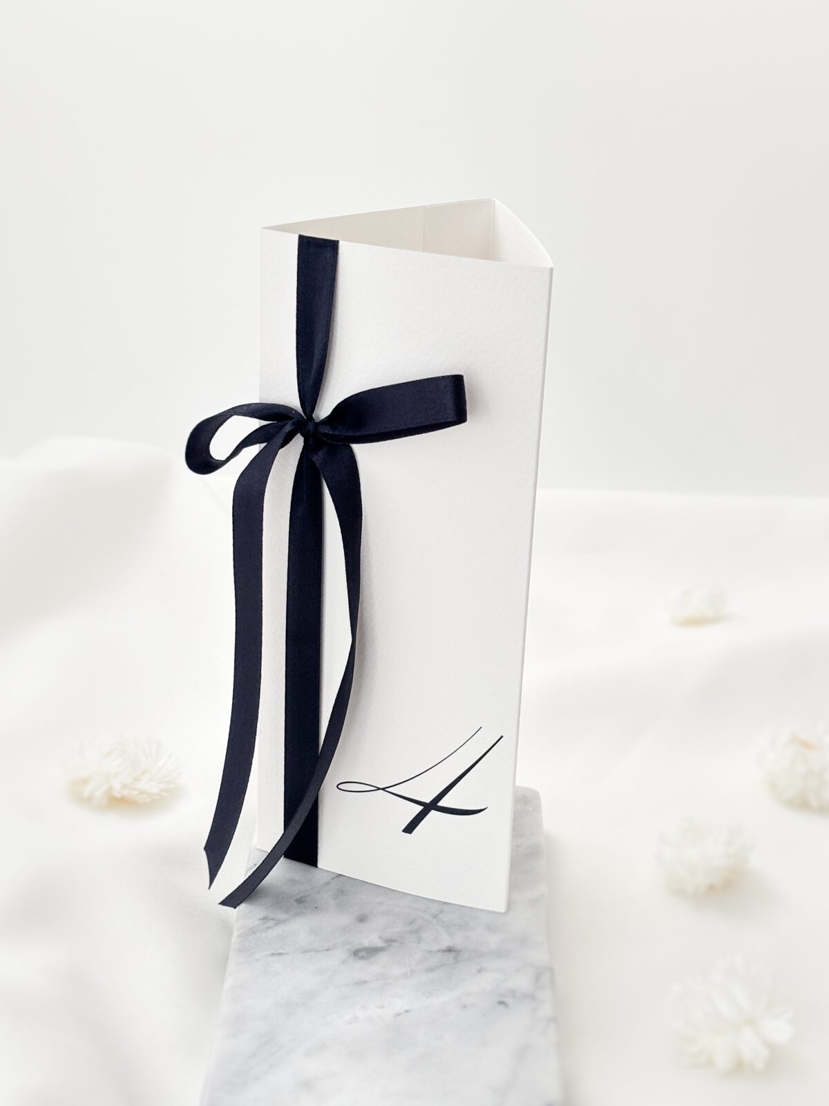 elegancki numer stołu weselnego z czarną wstażką, styl old money