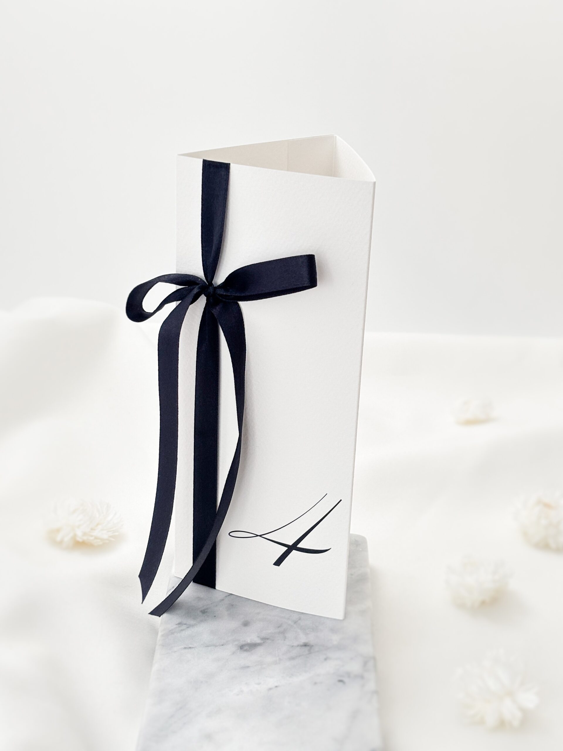 elegancki numer stołu weselnego z czarną wstażką, styl old money