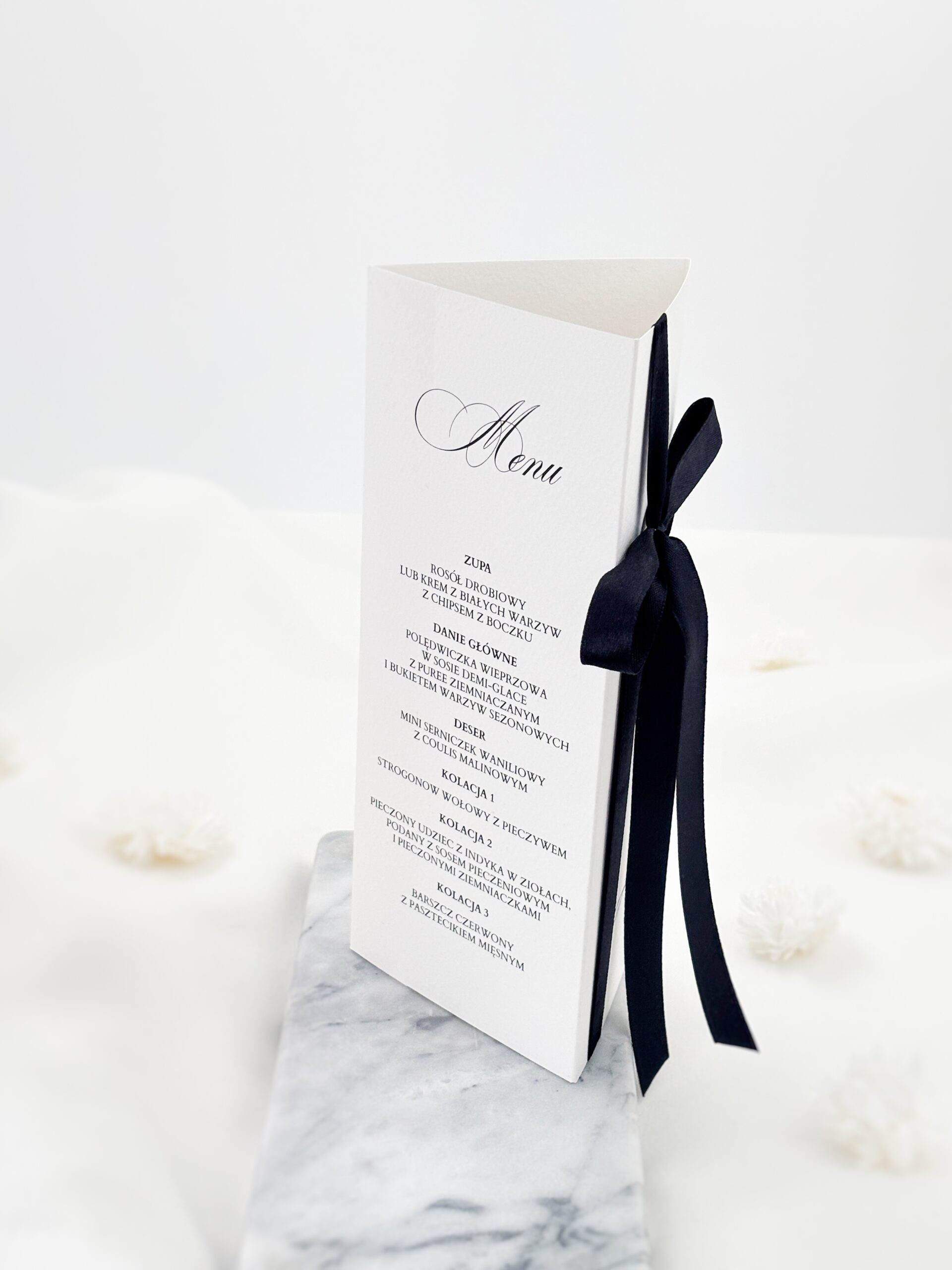Menu stojące z czarną kokardą i listą dań weselnych