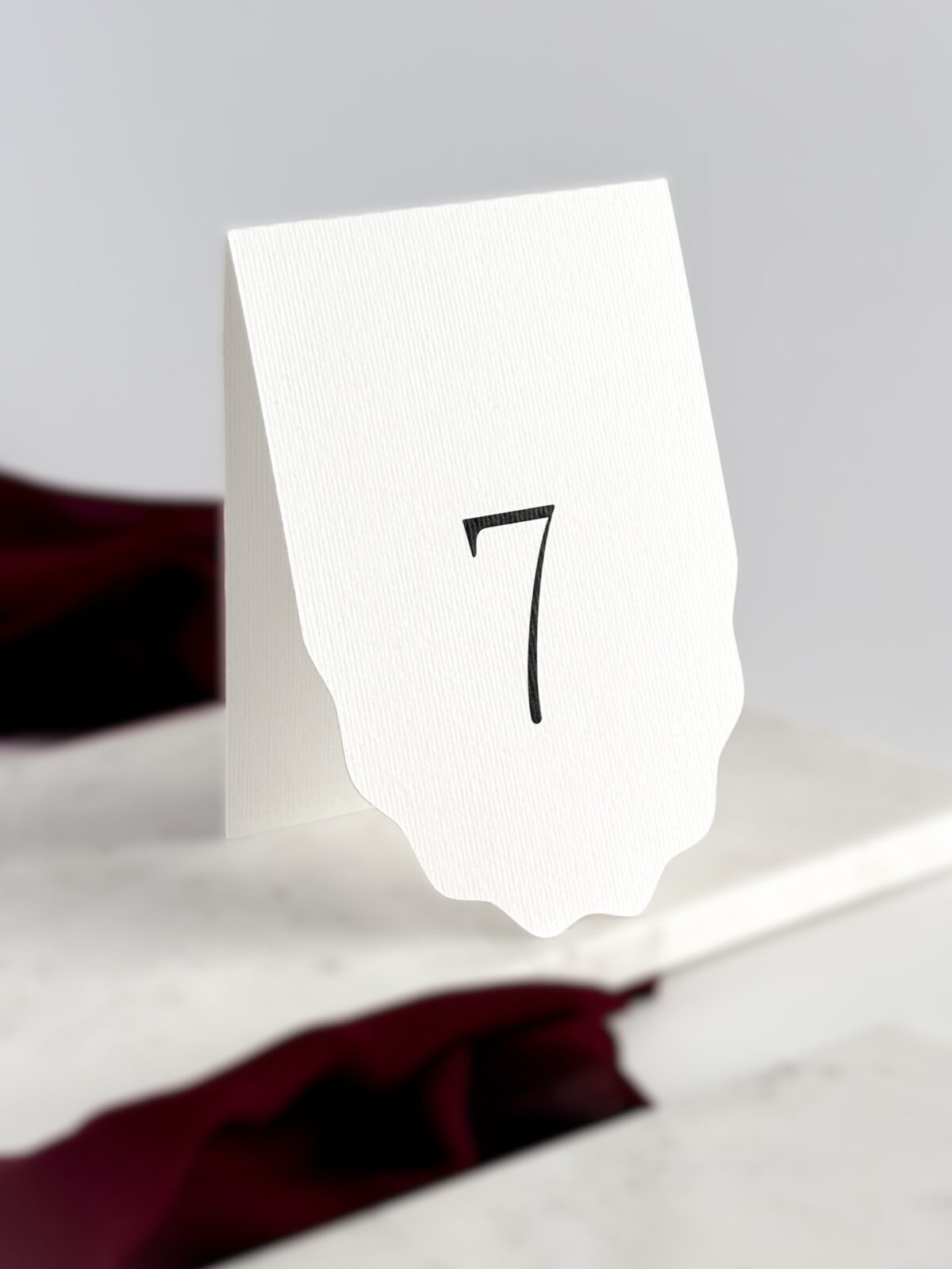 Minimalistyczny numer stołu, biała karta z dekoracyjnym dołem, minimalizm i czytelność