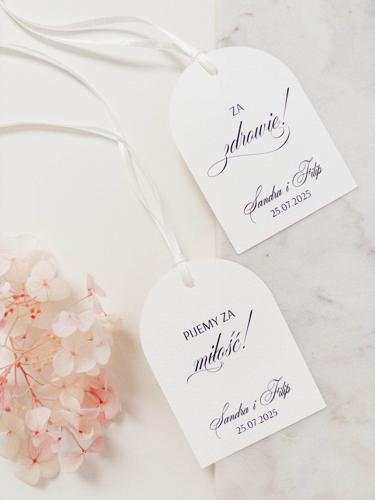 Zawieszki Zoya na alkohol z elegancką kaligrafią, zaokrągloną formą i białą tasiemką