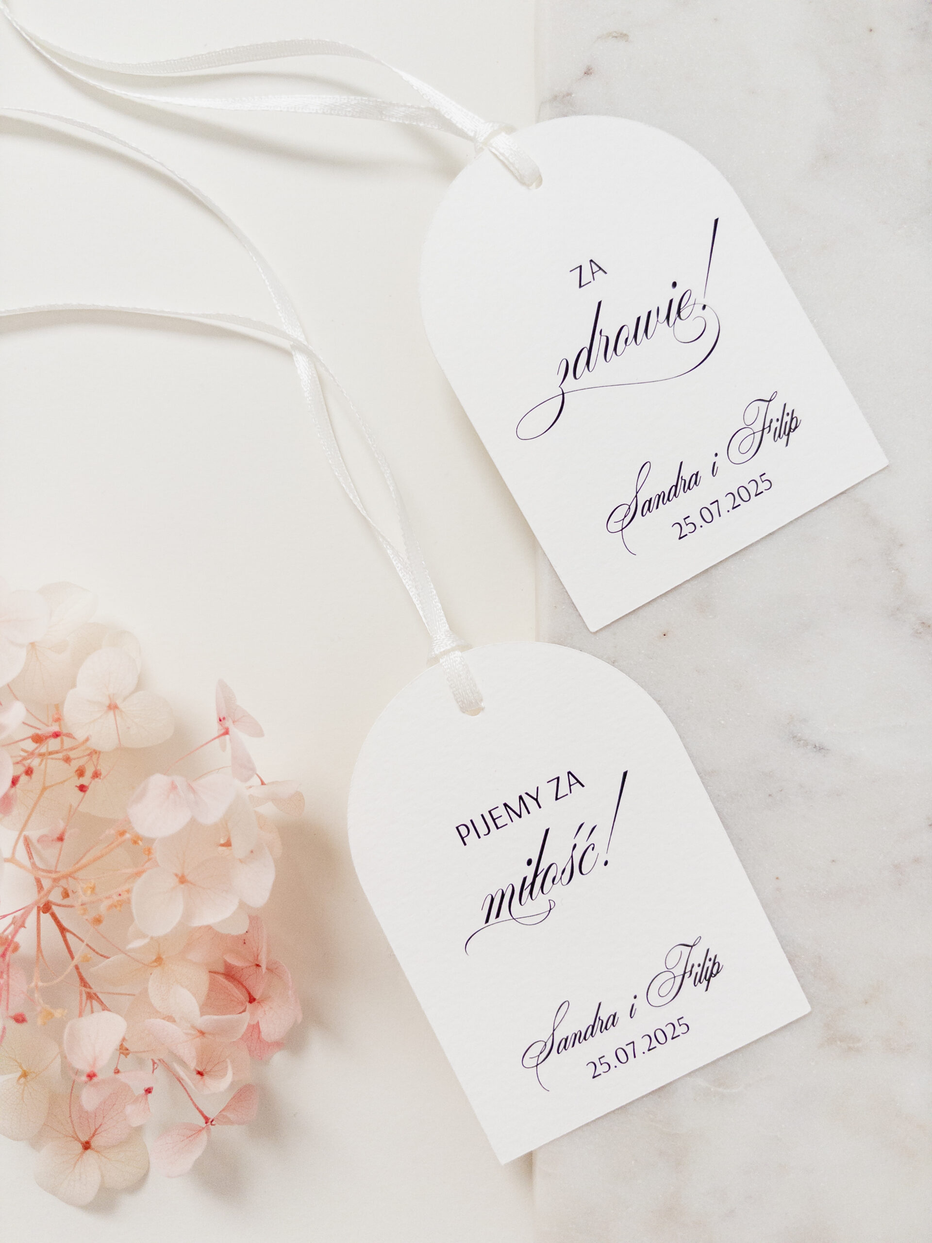 Zawieszki Zoya na alkohol z elegancką kaligrafią, zaokrągloną formą i białą tasiemką