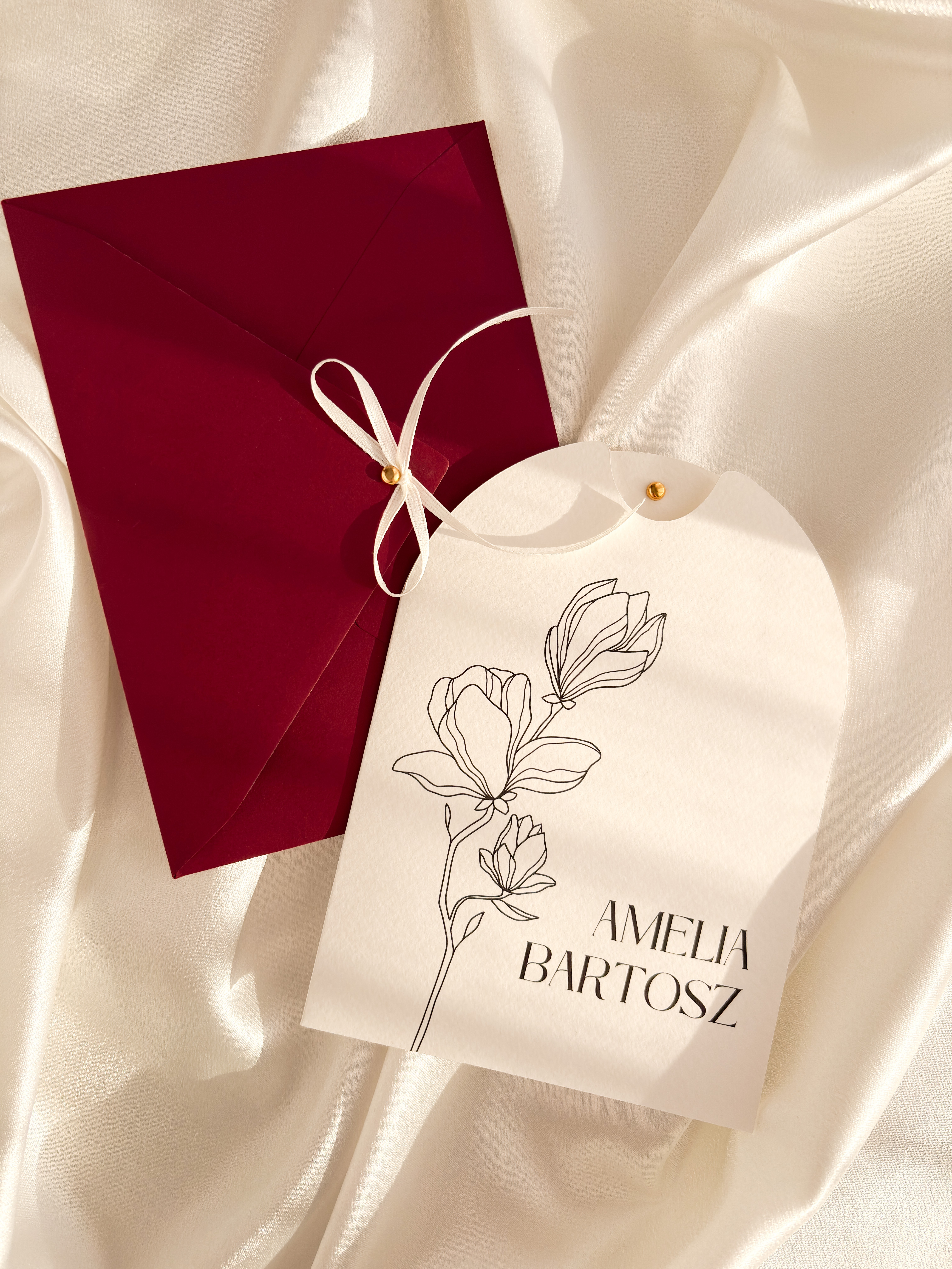 romantyczne zaproszenie ślubne z motywem magnolii, koperty w kolorze burgundowym