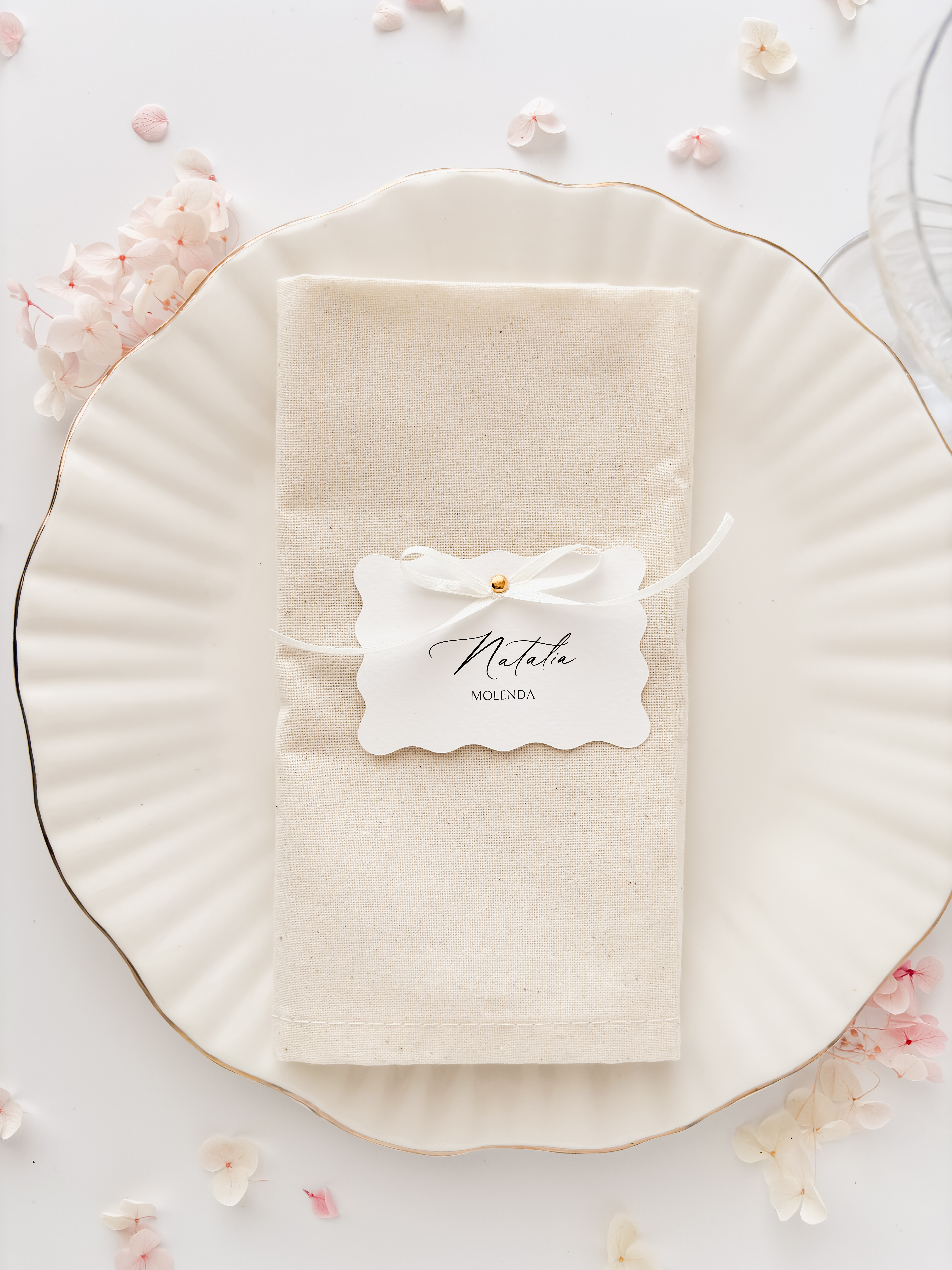 Winietka w kształcie fali z kokardką o wymiarach 8 x 5,5  cm, drukowana na białym papierze fakturowanym o gramaturze 250g.